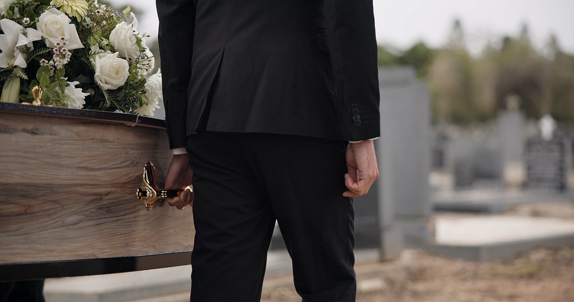 Coffin, hands and man walking at funeral ceremony outdoor with pallbearers at tomb. Death, grief an